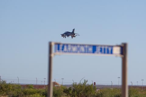 A plane flies over a sign highlighting the Learmonth air base in Exmouth. 