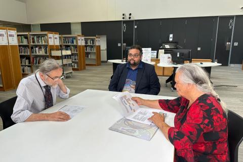 Mark Chambers (left) and Duane Kelly helping Roma Winmar research her family history at the State Library.