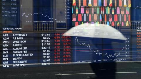 Person reflected in window of ASX display board