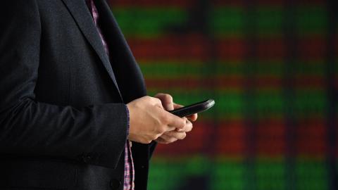 Person uses phone near ASX display board